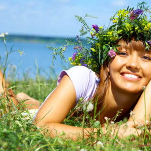 woman with flower crown on field, smiling and happy