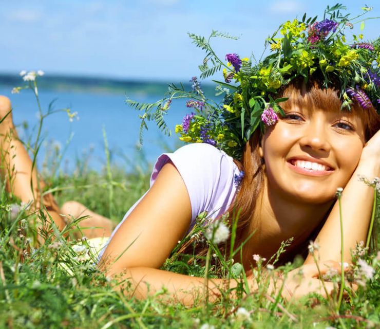woman with flower crown on field, smiling and happy