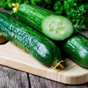 Fresh english cucumbers on a wooden board on rustic table with blue cloth