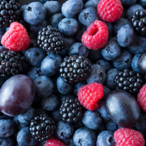 Background of fresh fruits and berries. Ripe blackberries, blueberries, plums, raspberries.
