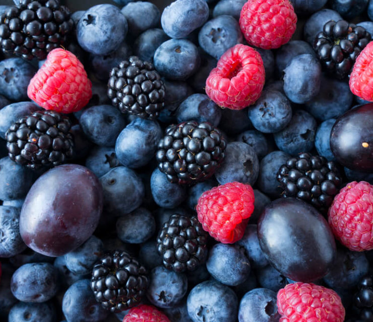 Background of fresh fruits and berries. Ripe blackberries, blueberries, plums, raspberries.