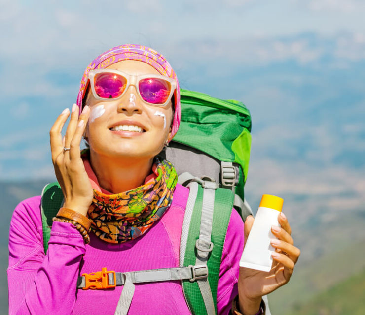 Hiker woman applying sunscreen with harmful ingredients