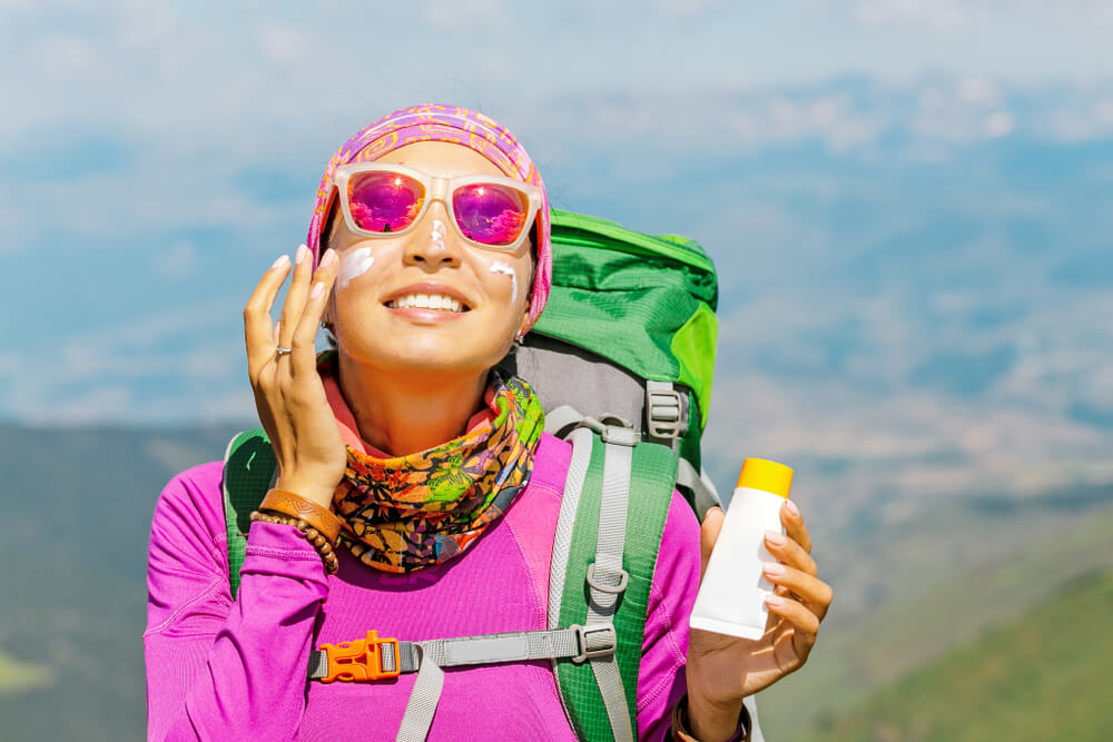 Hiker woman applying sunscreen with harmful ingredients