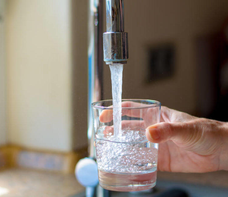 woman filling glass of water with fluoride
