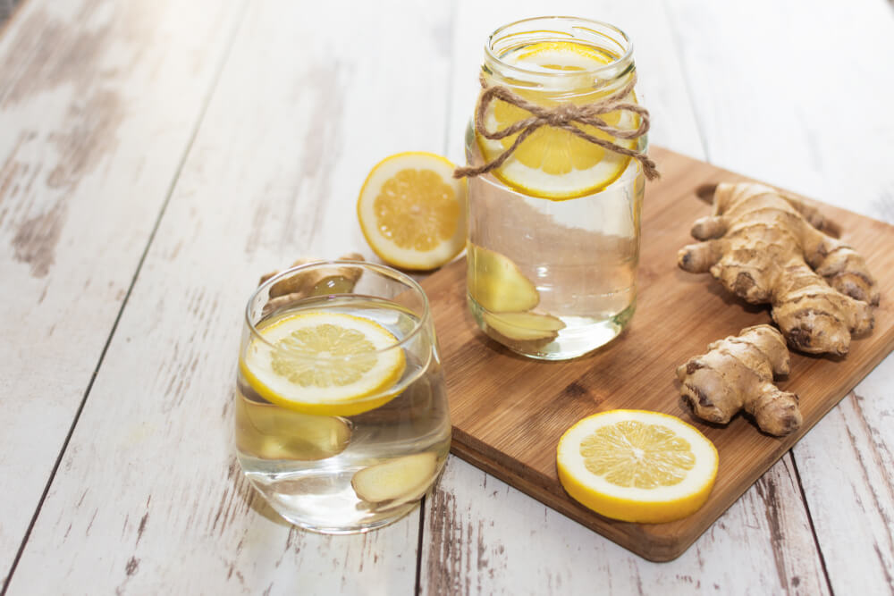 Ginger with lemon detox water in the morning on wooden background.
