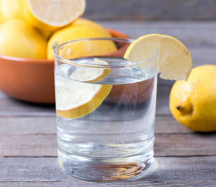 lemon water with bowl of lemons in back