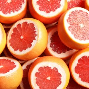 Many sliced fresh grapefruits as background, top view