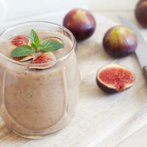 Fig smoothie served in glass with mint leaves