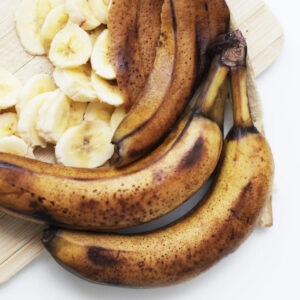 Ripe banana brown skin. Wooden cutting board. Sliced banana background. Bunch of over riped bananas. Food waste background. Food scraps use. Healthy smoothie preparation. Rotten brown bananas.