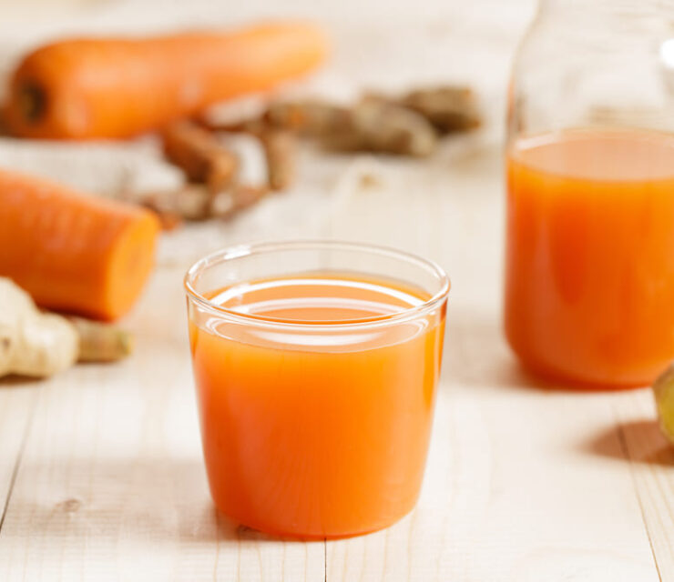 Carrots, ginger, turmeric detox fresh juice on wooden background. Healthy vegetarian food concept.