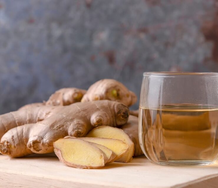 Cup of tea with ginger root on a wooden table, Ginger tea with and honey on a gray background.