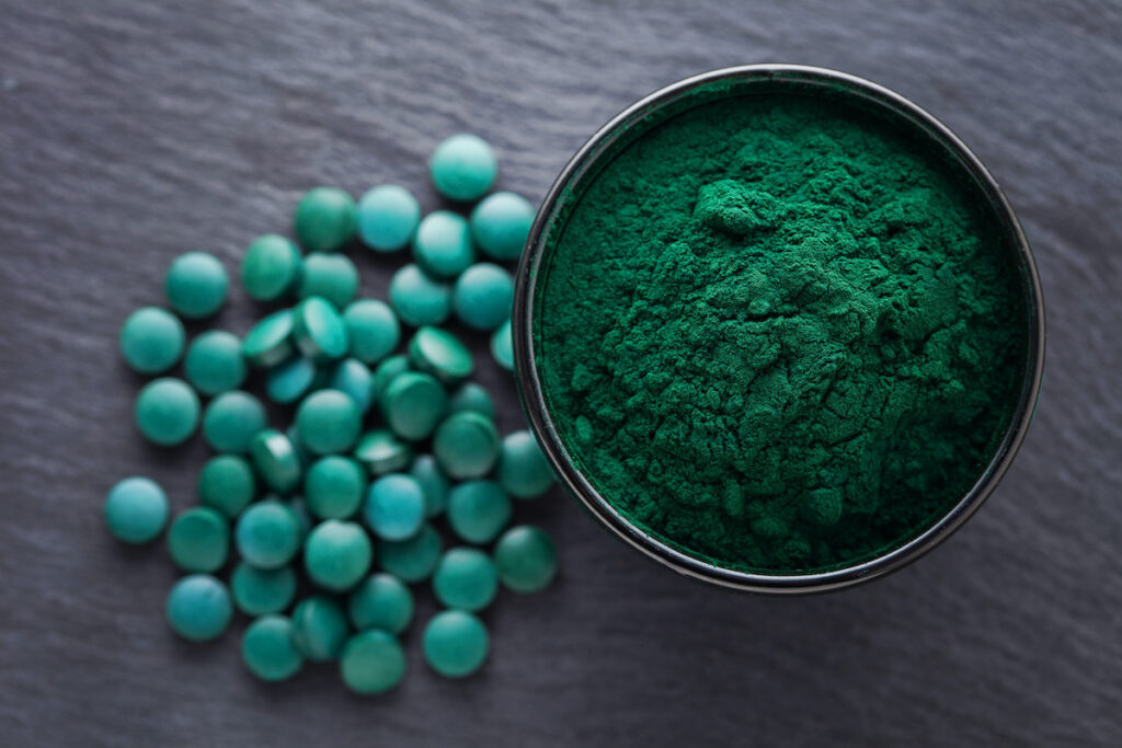 spirulina powder and tablets on wooden table