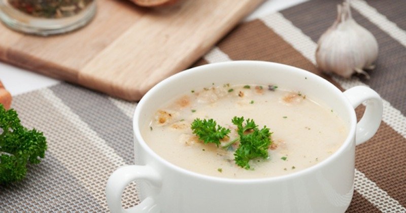 cup of garlic soup with parsley on top