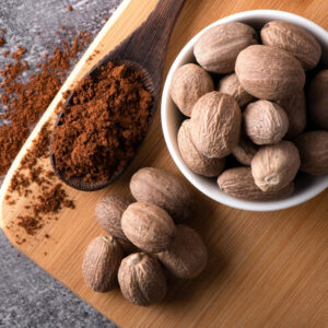 Nutmeg macro in a bowl. Nutmeg powder. Nutmeg spice in a wooden spoon.