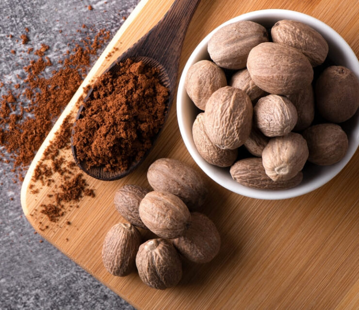 Nutmeg macro in a bowl. Nutmeg powder. Nutmeg spice in a wooden spoon.
