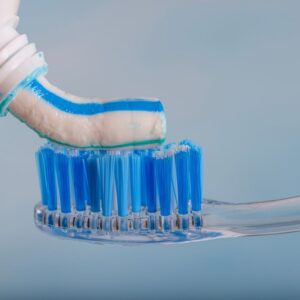 Toothbrush and toothpaste, Squeezing toothpaste onto toothbrush. Applying toothpaste on brush against blurred background, closeup.