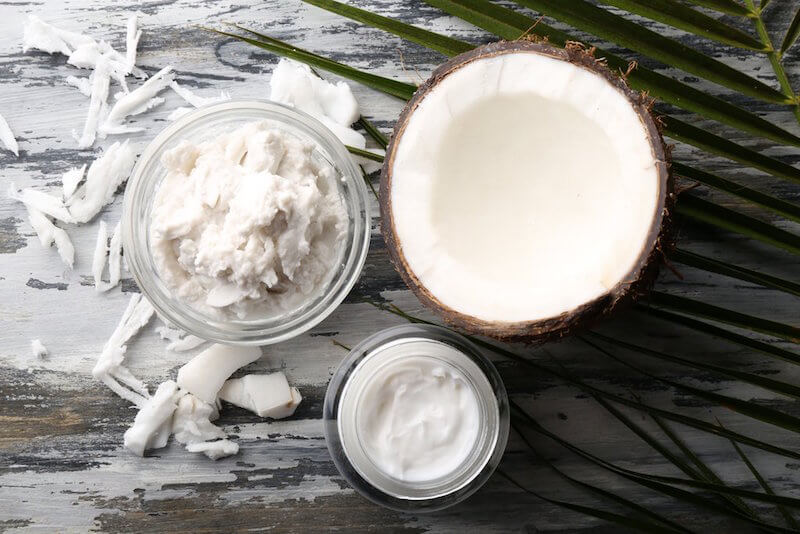 A coconut, a bowl of coconut meat and hardened coconut oil