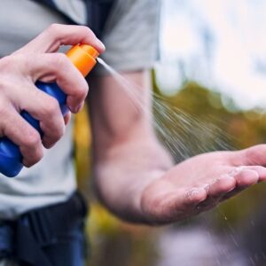 Sunscreen spray, hand and closeup while hiking for security from the sun and health in summer. Exercise, nature and a man with a bottle with cream for skincare and safety from sunshine for fitness