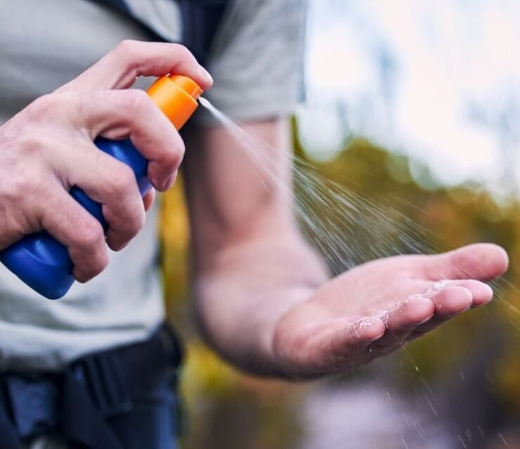 Sunscreen spray, hand and closeup while hiking for security from the sun and health in summer. Exercise, nature and a man with a bottle with cream for skincare and safety from sunshine for fitness