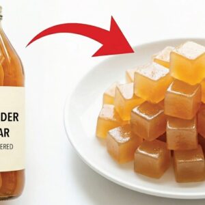 Apple cider vinegar gummies on a white plate with a bottle of apple cider vinegar and a red arrow pointing to the gummies