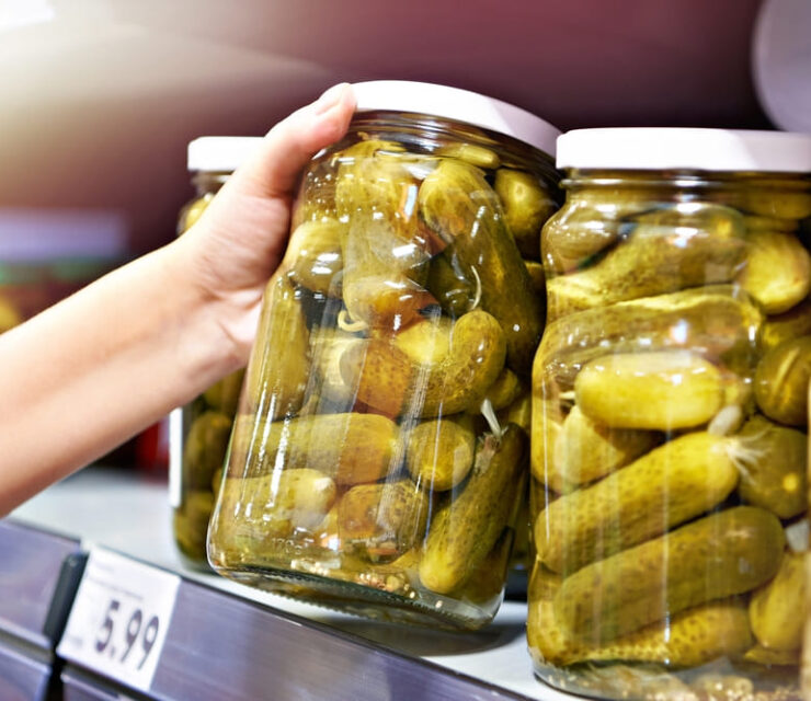 Canned pickles in hands in store