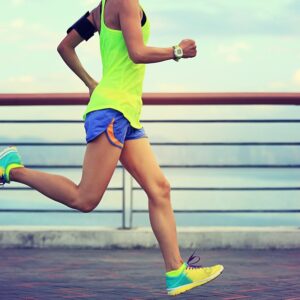 woman running on cement with lake in background