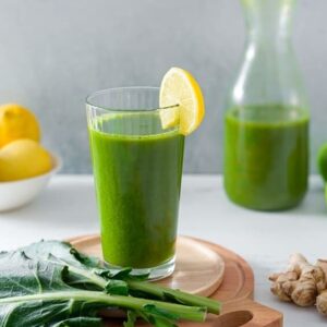 Organic healthy green juice made from leafy greens, lemon, green apple, and ginger root with copy space