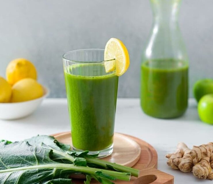 Organic healthy green juice made from leafy greens, lemon, green apple, and ginger root with copy space